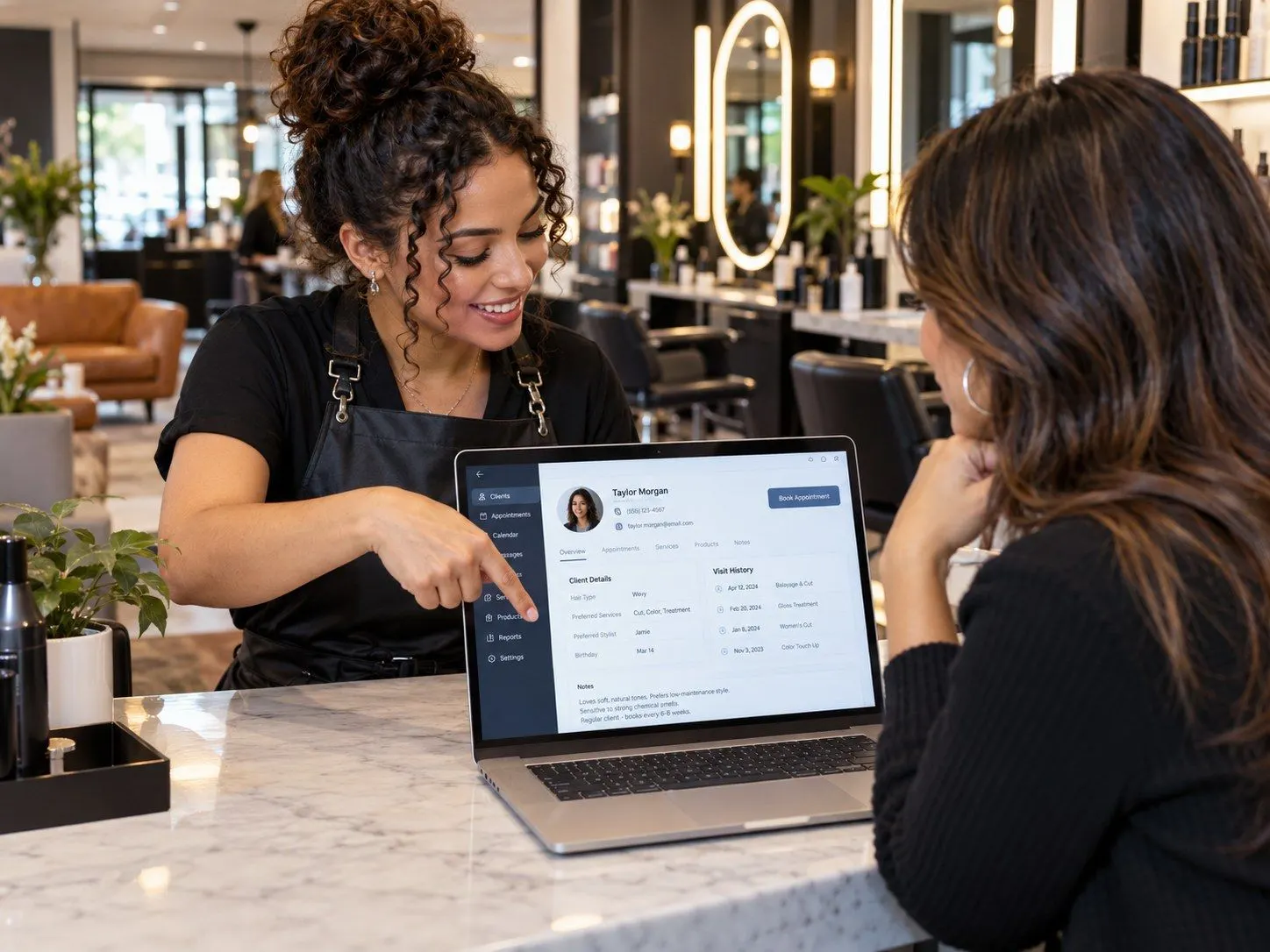 Stylist showing a client her client card on a laptop